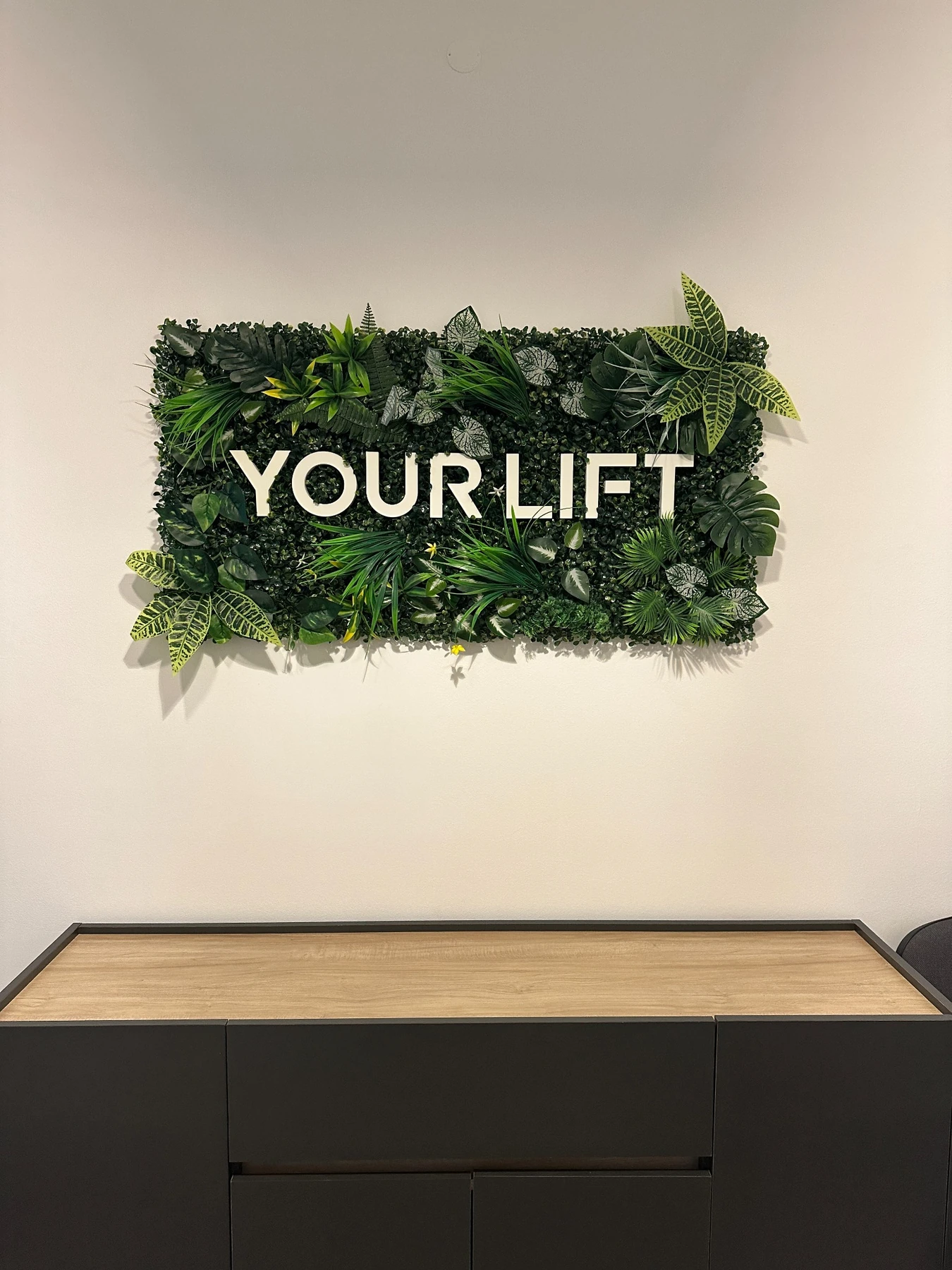 Entrada do estúdio Your Lift — logótipo sobre o jardim vertical